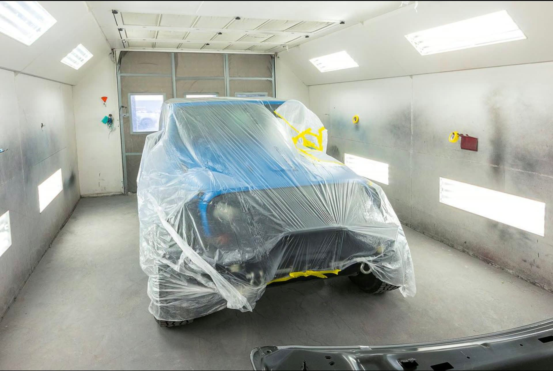 Vehicle plastic-wrapped between coats inside the paint booth