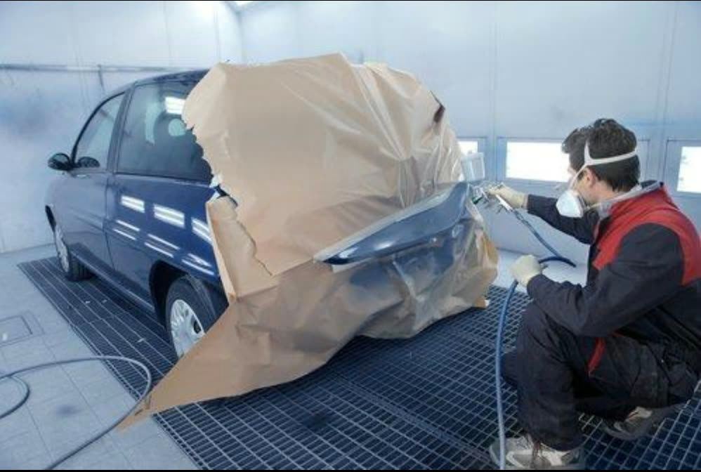 Painter masking a vehicle in the spray booth